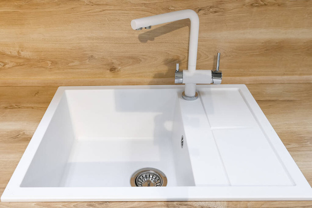 Modern beyaz kare lavabo, yumuşak ahşap mutfak yüzeyine yerleştirilmiş uzun musluk. - Fotoğraf, Görsel