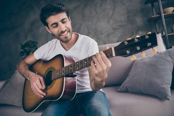 Closeup photo of mixed race guy sitting sofa hold acoustic instrumental guitar playing new written song sound love his hobby creative talented person flat loft living room indoors - Fotó, kép