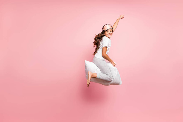 Full length body size view of nice attractive childish playful comic cheerful cheery wavy-haired pre-teen girl jumping riding pillow purpose goal party isolated over pink pastel color background - Photo, image