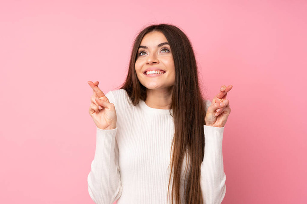Young woman over isolated pink background with fingers crossing - Photo, Image