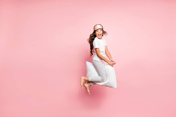 Full length body size view of her she nice attractive crazy funky cheerful cheery wavy-haired pre-teen girl jumping having fun riding pillow party isolated over pink pastel color background - Photo, image