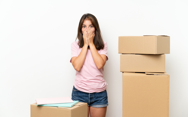 Young girl moving in new home among boxes with surprise facial expression - Zdjęcie, obraz
