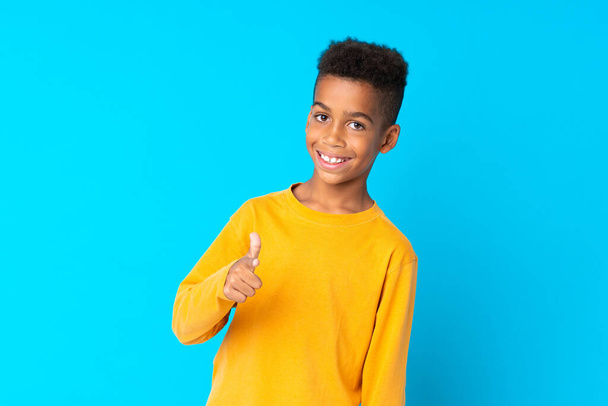 El chico afroamericano sobre un fondo azul aislado te señala con el dedo con una expresión confiada
 - Foto, imagen