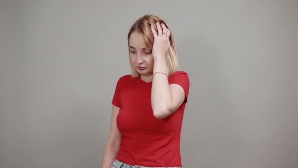 Mujer bastante joven posando aislada en la pared gris escéptica vista impactada
 - Imágenes, Vídeo