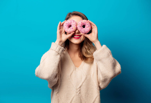 Style woman in sweater with donut on blue background - Фото, изображение