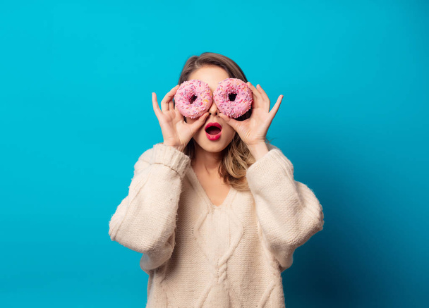 Style woman in sweater with donut on blue background - Foto, imagen
