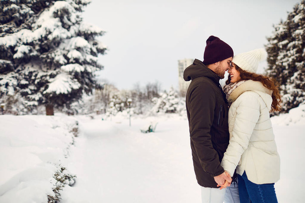 Young couple on the snow in winter in the park - Foto, afbeelding