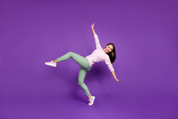 Full length body size photo of cheerful cute positive charming youngster balancing with hands thrown aside with emotional face expression isolated over purple vivid color background dancing - Fotoğraf, Görsel