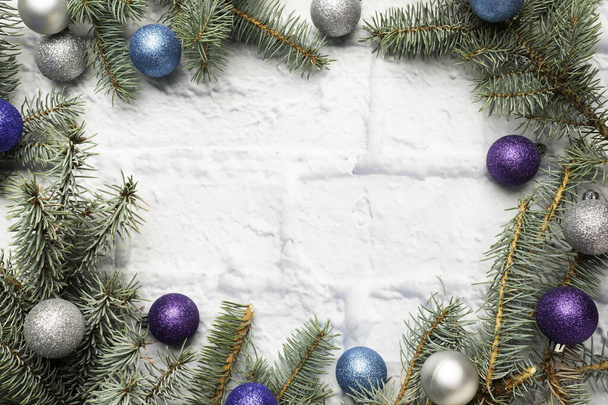 Kerst frame gemaakt van sparren, kerstboom decoraties in zilver en blauw op een lichte bakstenen achtergrond. Begrepen, ruimte. Vlakke plaat. - Foto, afbeelding