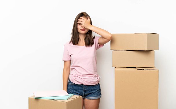 Chica joven moviéndose en un nuevo hogar entre cajas cubriendo los ojos por las manos
 - Foto, imagen