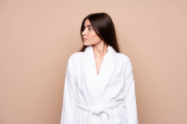 Young girl in a bathrobe over isolated background looking side - Foto, Bild