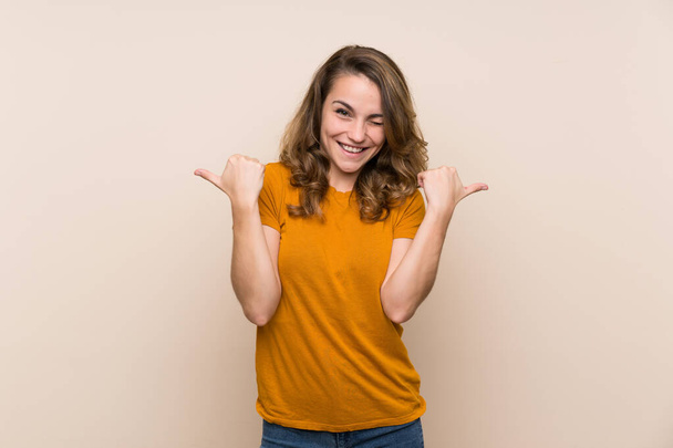 Young blonde girl over isolated background with thumbs up gesture and smiling - Foto, Imagem