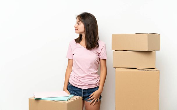 Mladá dívka pohybující se v novém domově mezi krabicemi hledající do strany - Fotografie, Obrázek