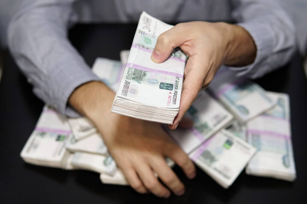 чоловічі руки досягають грошей. Мільйон рублів на чорному столі. Поняття багатства, успіху, жадібності та корупції, бажання грошей
 - Фото, зображення