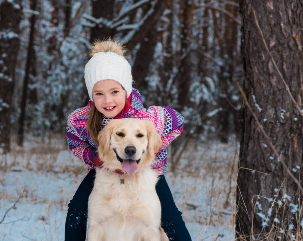 veselá dívka objímání s úsměvem pes zlatý retrívr ve sněhu venku - Fotografie, Obrázek