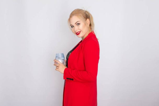 Blonde woman holding water glass over light background - Photo, Image