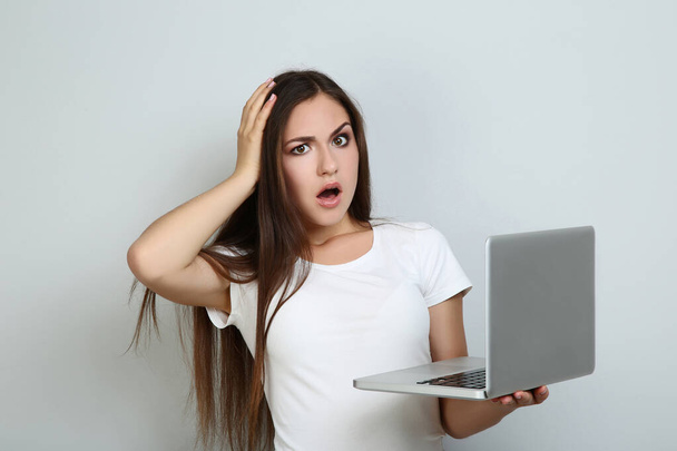 Young girl with laptop computer on grey background - Zdjęcie, obraz