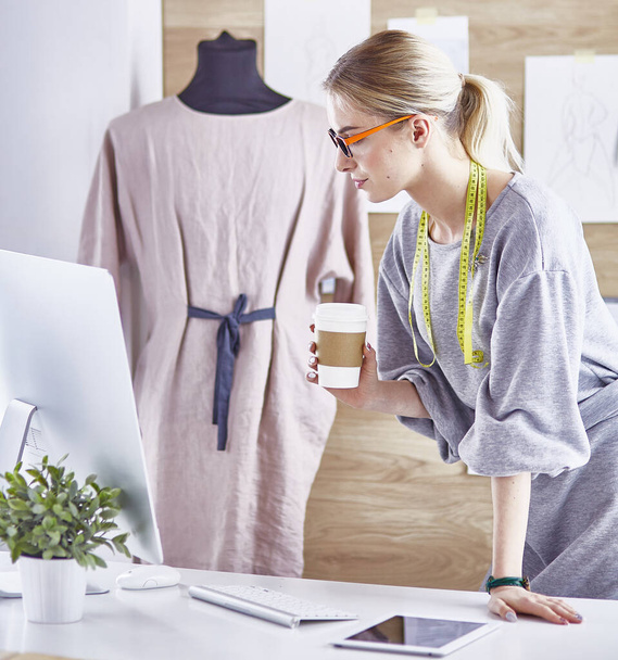 Attractive fashion designer working in office, leaning on desk, drawing - Valokuva, kuva
