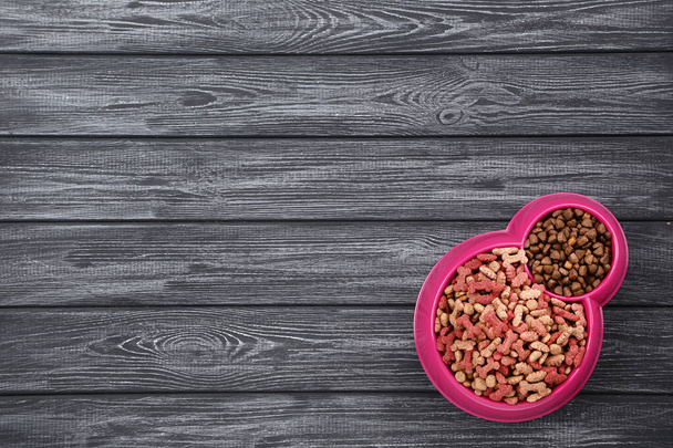 Dry pet food in bowl on black wooden table - 写真・画像