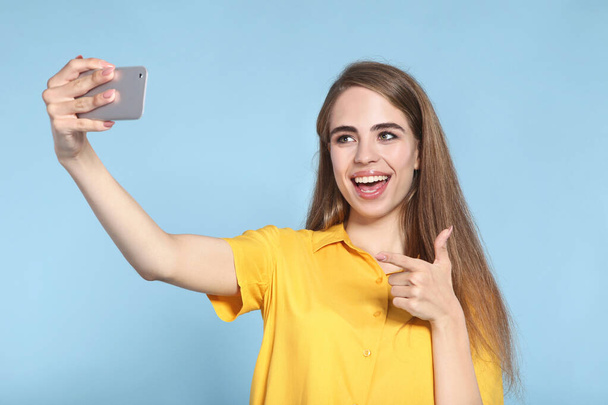 Young beautiful girl showing thumb up and making selfie on smart - Фото, изображение
