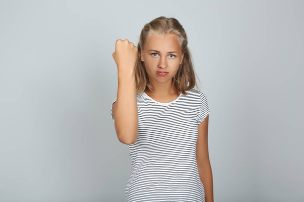 Portrait of young girl showing a fist on grey background - Фото, зображення
