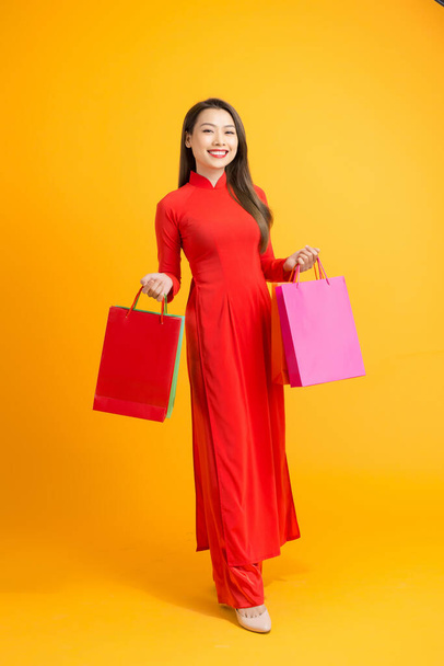 Vietnamesin in traditioneller ao dai-Kleidung und mit Einkaufstaschen in der Hand auf weißem Hintergrund - Foto, Bild
