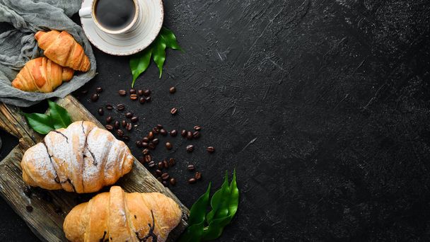 Cup of coffee with croissant. Breakfast. On a black stone background. Top view. Free space for your text. - Photo, image