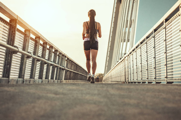 Ajustar muscular joven corredor corriendo a gran velocidad al aire libre en el puente del río
. - Foto, Imagen