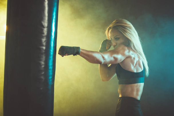 Жінка боксер тренується активно і важко, вдаривши величезний мішок удару
. - Фото, зображення