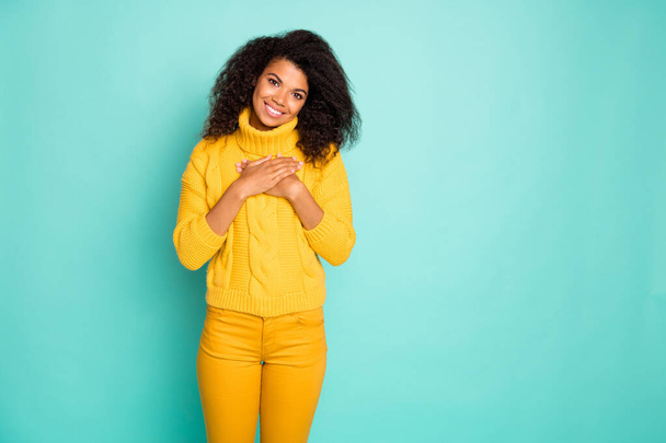 Photo of dreamy dark skin wavy lady holding hands on chest eyes closed harmony wear yellow knitted pullover stylish pants isolated blue teal color background - Foto, Imagem