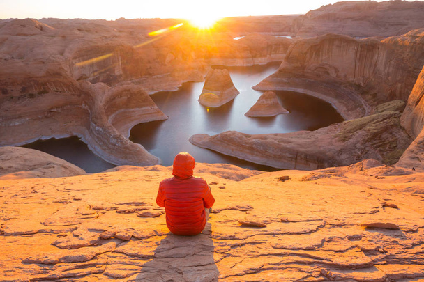 Fundo natural incomum. Reflexão Canyon no Lago Powell, Utah, EUA. Inspirador caminhadas cena-homem descansando sobre o belo pôr do sol
. - Foto, Imagem