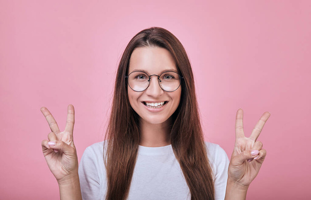 Cool girl smiling slightly and shows fingers peace - Фото, зображення