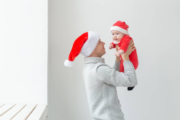 Concept de paternité et vacances - Père avec son petit garçon portant des chapeaux de Père Noël célébrant Noël
 - Photo, image