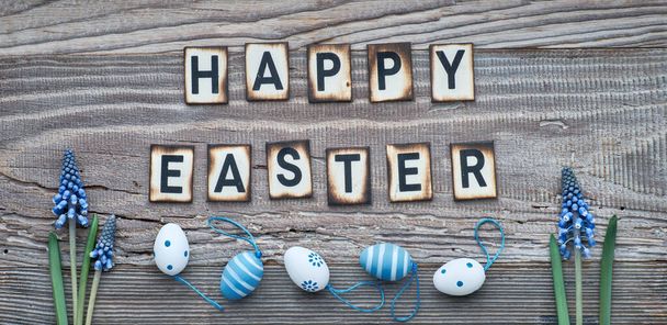 Happy Easter text on rustic wood with blue grape hyacinth flowers and Easter eggs - Zdjęcie, obraz