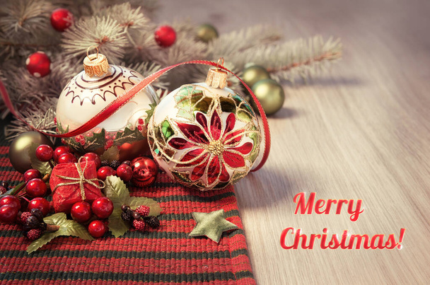 Tahta masada kırmızı ve yeşil Noel süsleri olan tebrik kartı, "Mutlu Noeller!" - Fotoğraf, Görsel