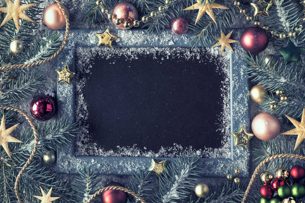 Yeşil, pembe ve altın rengi bir Noel arkaplanı ve boş bir kara tahtası var. Köy tahtasında karla süslenmiş tebeşir dalları. Kopyalama alanı olan üst görünüm. - Fotoğraf, Görsel