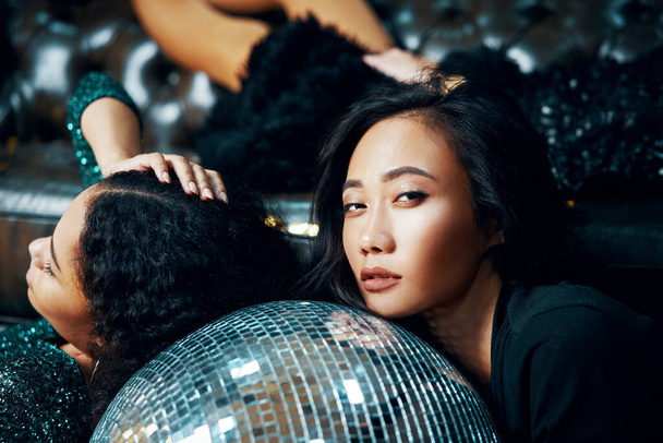 Pretty women relax and lying down on floor on disco ball in nightclub after crazy party - Zdjęcie, obraz