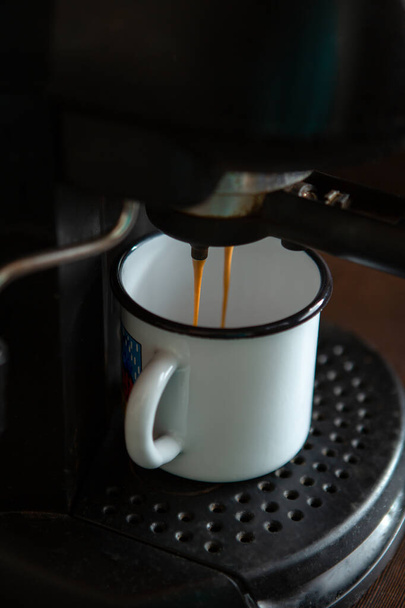 Photo of pouring coffee from coffee machine into mug in kitchen - Photo, Image