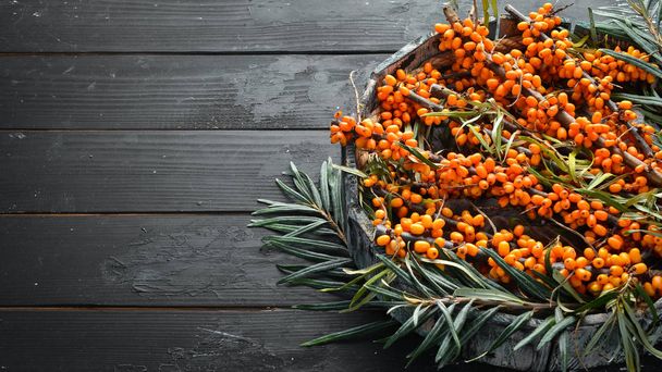 Sea buckthorn berries on black wooden background. Top view. Free space for your text. - Fotoğraf, Görsel