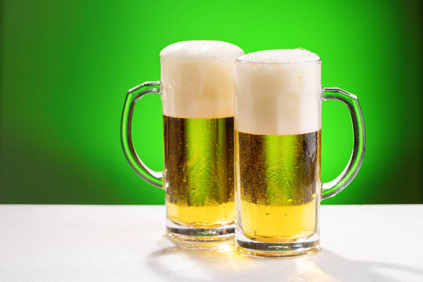 zwei Krüge Bier auf weißem Tisch. Konzept für St. Patrick 's Day. - Foto, Bild