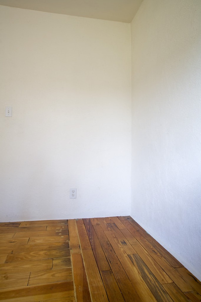 Quarto vazio com pisos de madeira e paredes brancas
 - Foto, Imagem
