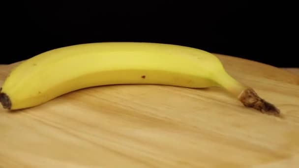 żółty banan obraca się o 360 stopni na drewnianej podstawce - Materiał filmowy, wideo