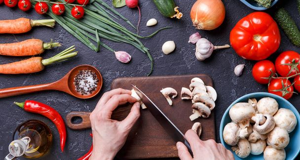 Picture on top of fresh vegetables, mushrooms, cutting board, oil, knife, hands of cook on table - Foto, afbeelding