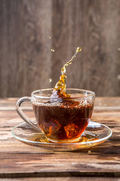 Spill tea in transparent mug on blank wooden background - Фото, зображення