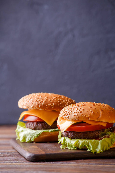 Foto van twee hamburgers op houten tafel op zwarte achtergrond - Foto, afbeelding