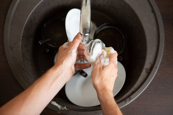 Изображение сверху человеческих рук, мыть посуду в раковину на кухне
 - Фото, изображение