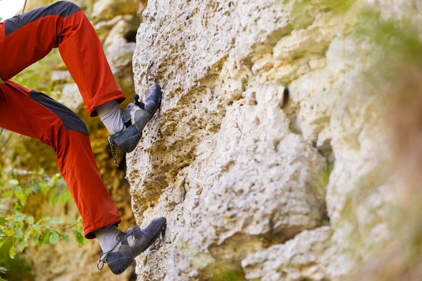 Imagen de los pies del hombre revoloteando sobre roca en el día de verano
 - Foto, Imagen