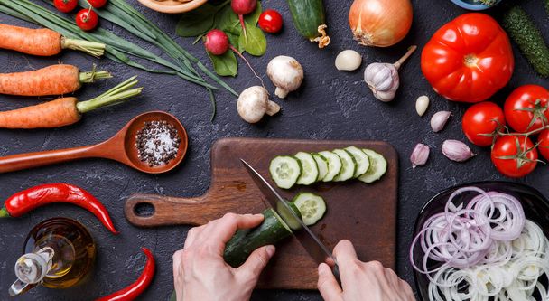 Foto op de top van verse groenten, champignons, snijplank, olie, mes, handen van kok op tafel - Foto, afbeelding