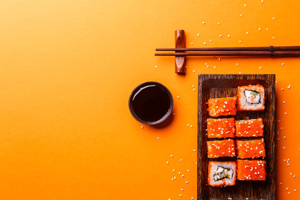 Rolls with chopsticks on empty orange background - Fotografie, Obrázek