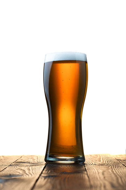 Milchglas mit hellem Bier auf Holztisch und weißem Hintergrund dahinter - Foto, Bild